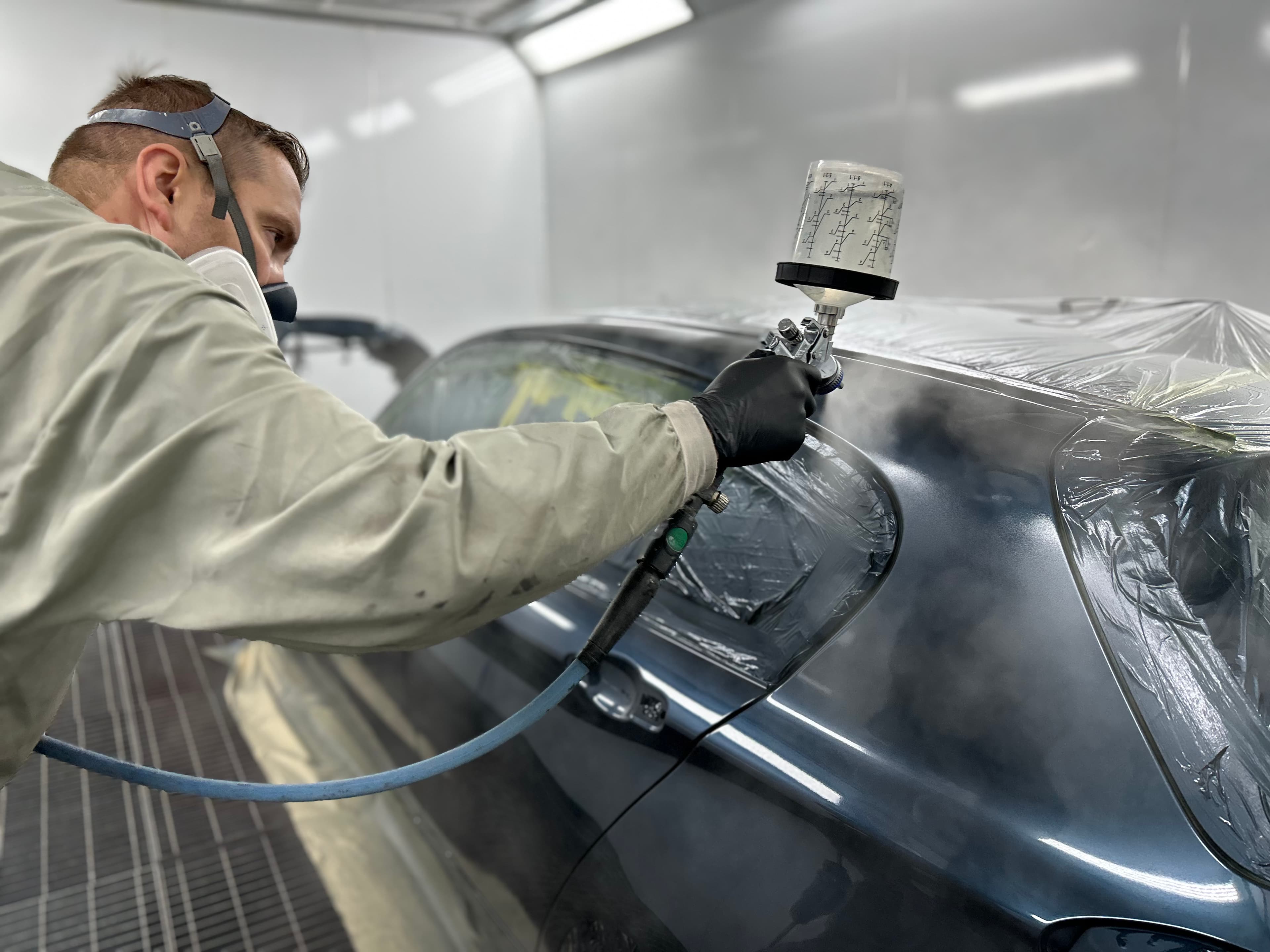 Technician carrying out scratch repairs on a car panel